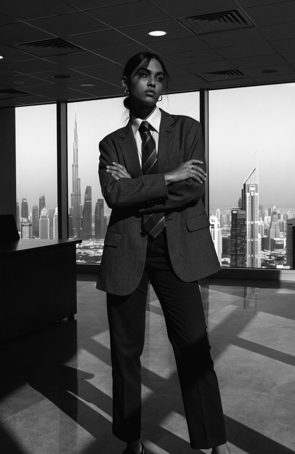 Businesswoman in a tailored suit standing in a high-rise Dubai office overlooking the city skyline